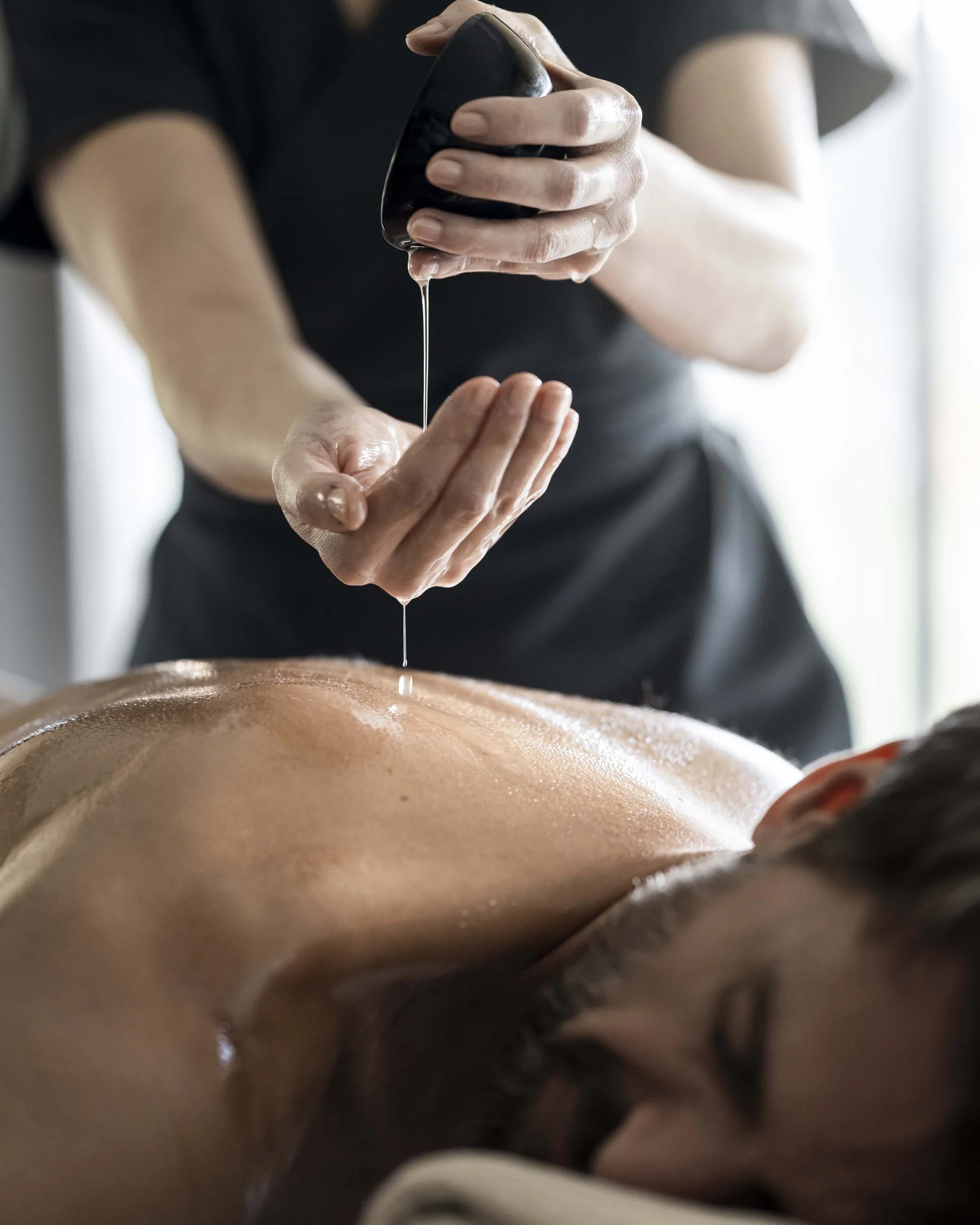 Mann bekommt Massage mit Öl, das aus einem Stein tropft