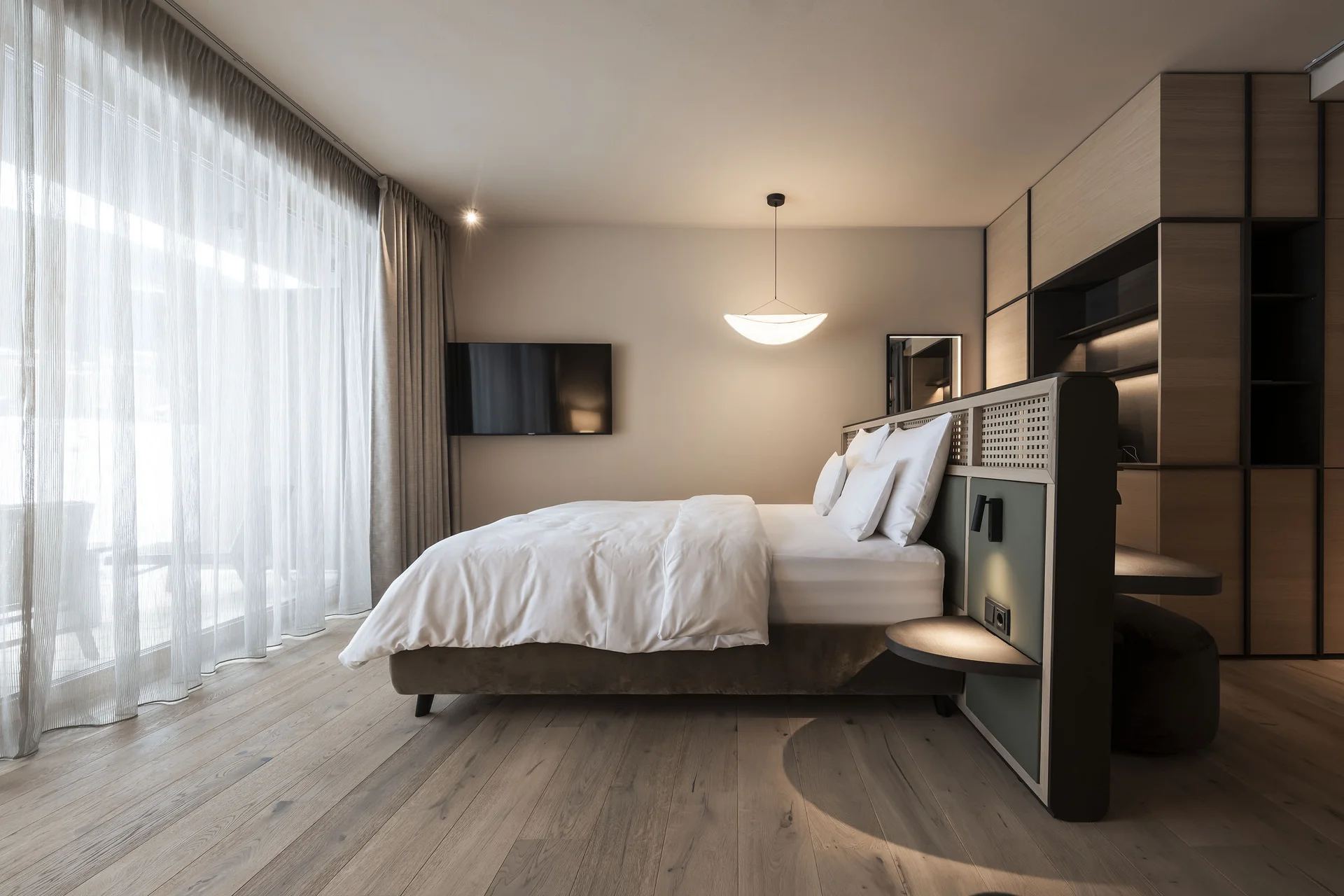 Modern bedroom with large bed and natural light through sheer curtains