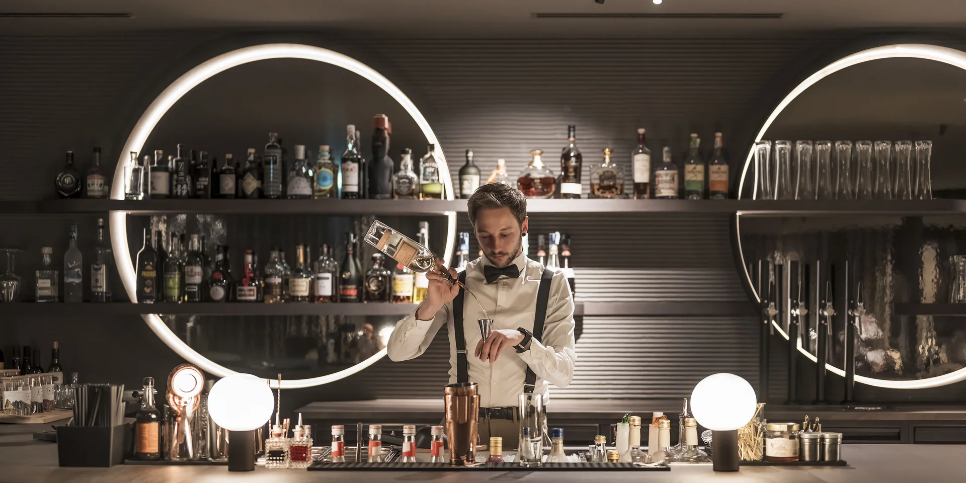 Barista elegante che prepara cocktail in un bar moderno con luci rotonde