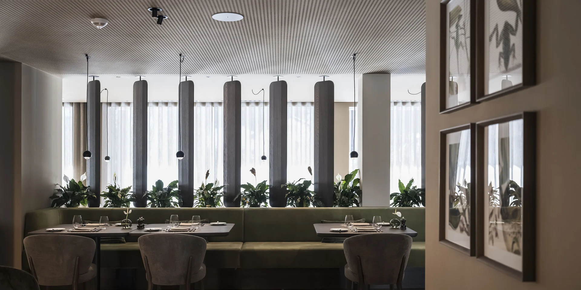 Interno di ristorante moderno con panca verde e piante vicino alla finestra