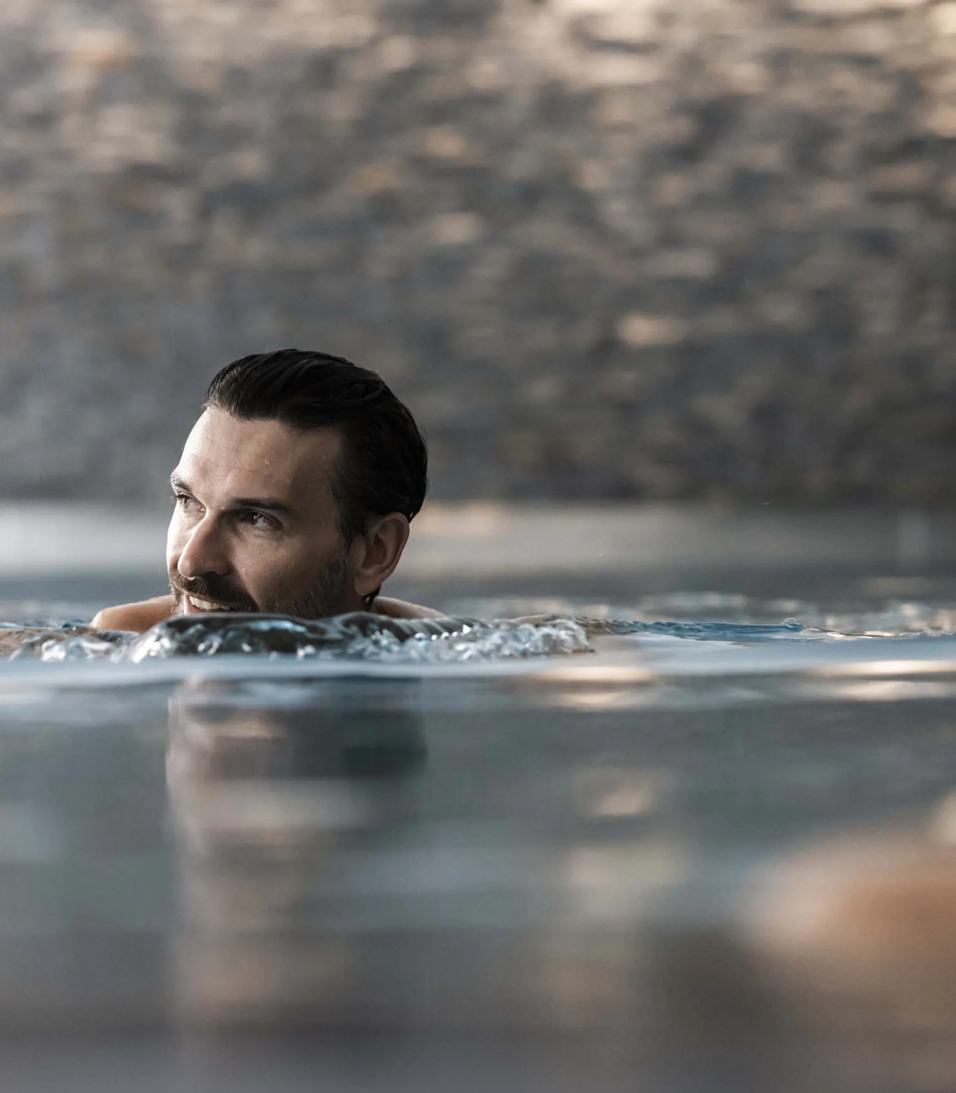 Mann entspannt im Schwimmbad mit Wasser um ihn