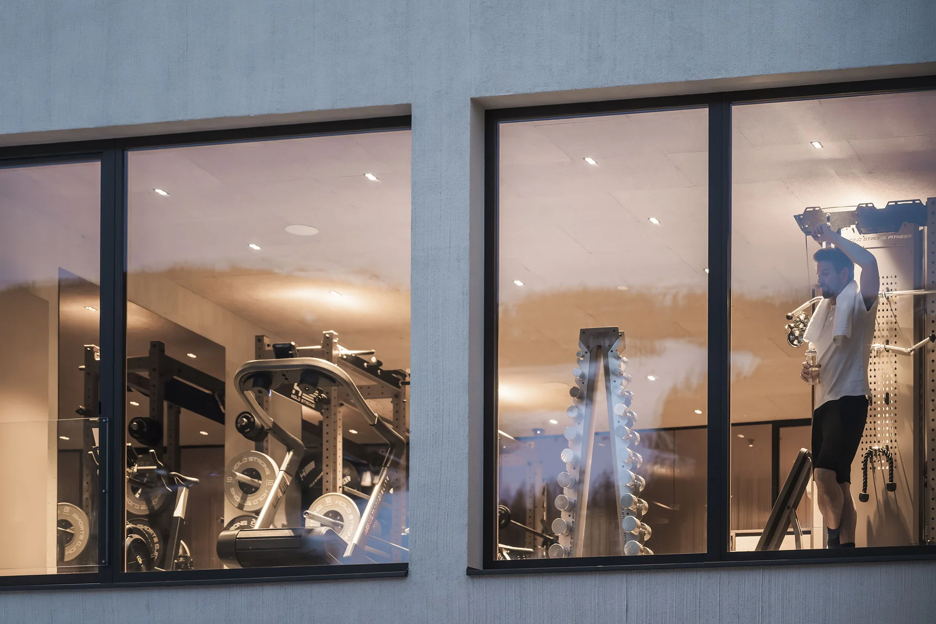 Vista attraverso la finestra di un uomo in palestra con pesi.