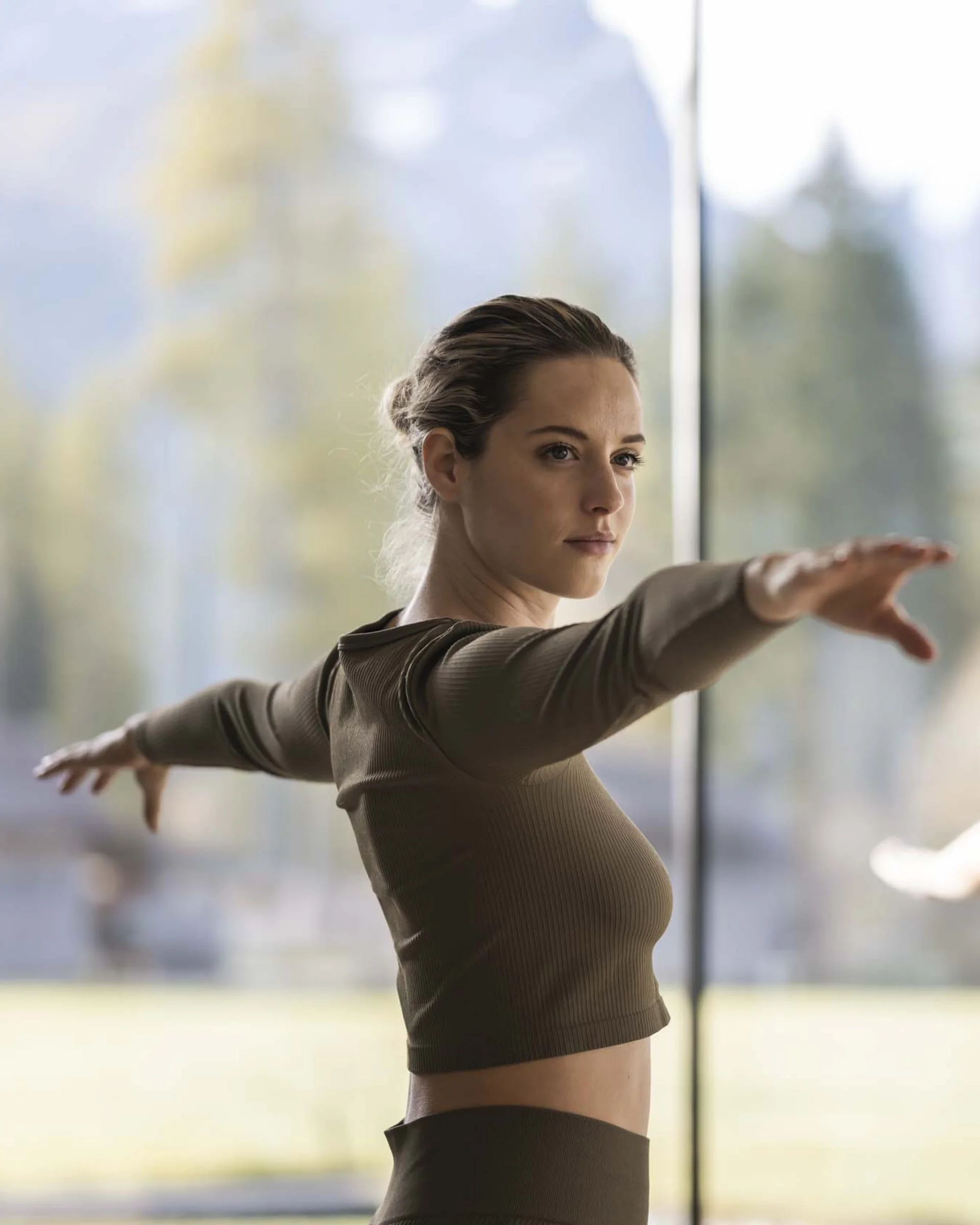 Zwei Frauen machen Yoga-Übung mit ausgestreckten Armen in hellem Raum
