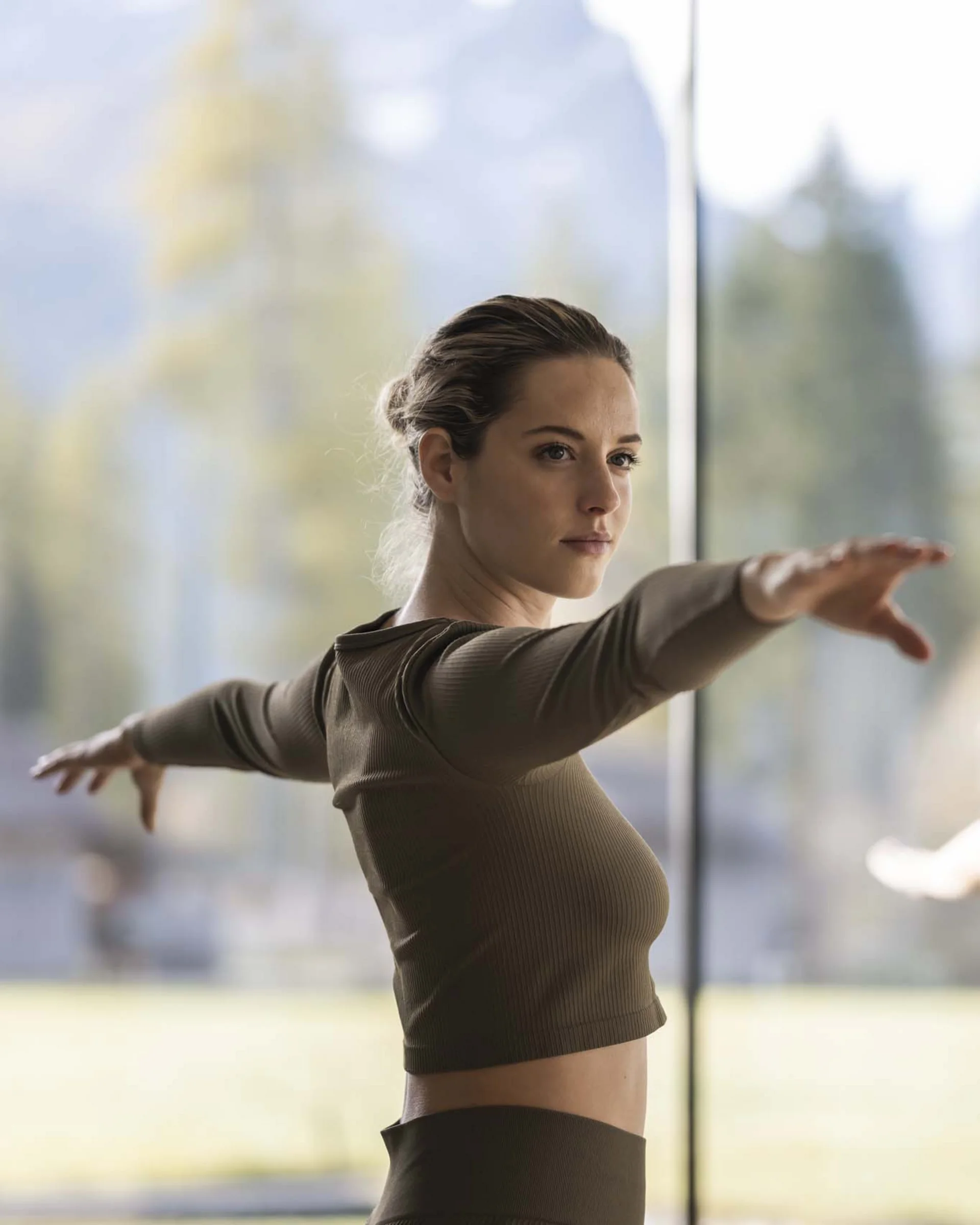 Zwei Frauen machen Yoga-Übung mit ausgestreckten Armen in hellem Raum