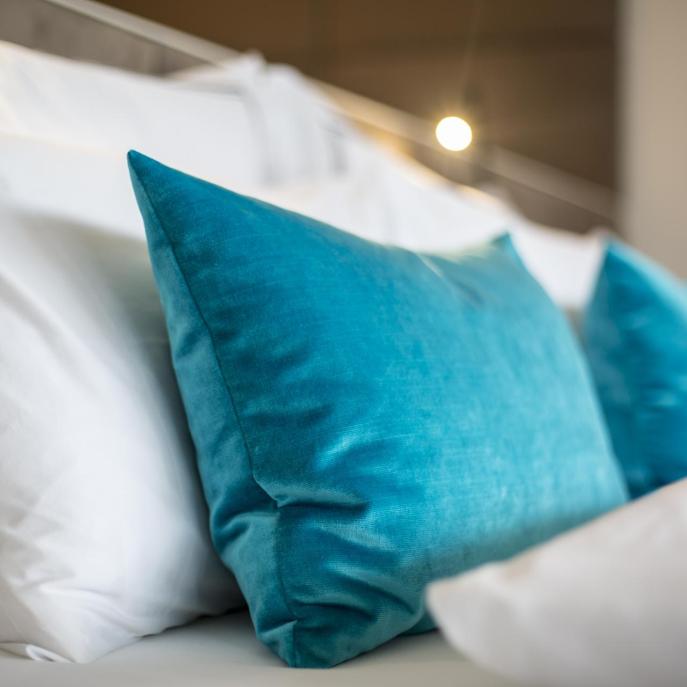 Cuscino blu su letto bianco